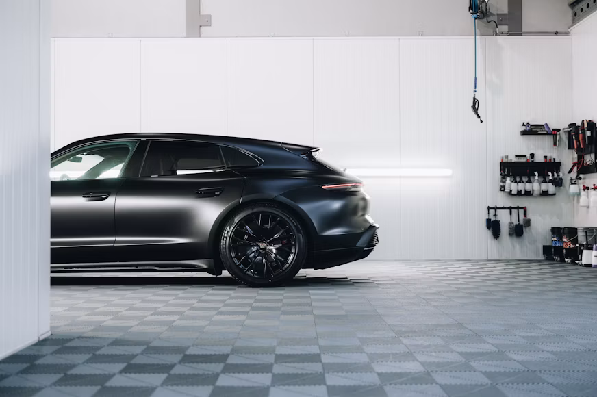 Glossy black sports car inside an automotive detailing garage